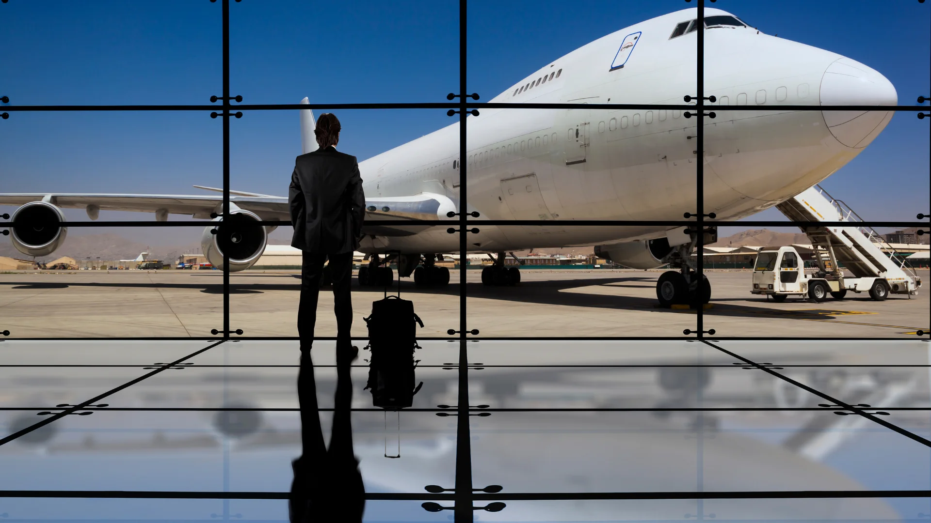 Homme d’affaires observant un avion à travers la baie vitrée d’un aéroport